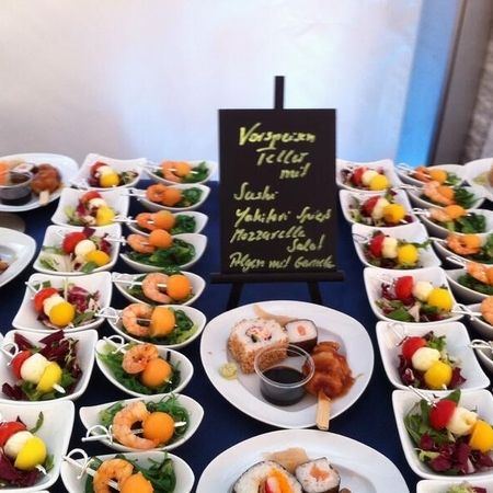 Vorspeisenteller mit Sushi, Garnelen, Mozzarella-Spießen und Salat in kleinen Schalen