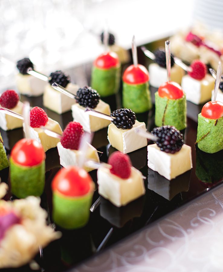 Elegante Fingerfood-Spieße mit Käse, Tomaten, Beeren und Gemüse auf schwarzer Servierplatte